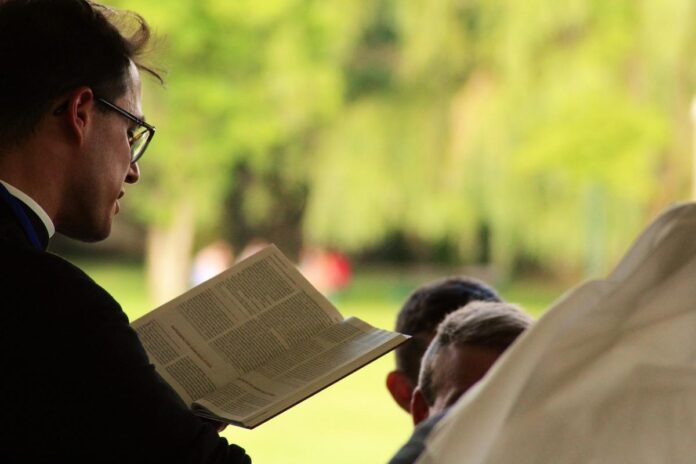 Sacerdote legge Bibbia in pubblico